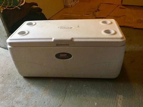 White cooler with handles on a concrete floor in a workshop setting